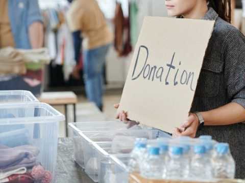 A nonprofit volunteer standing with a sign labeled “donation”