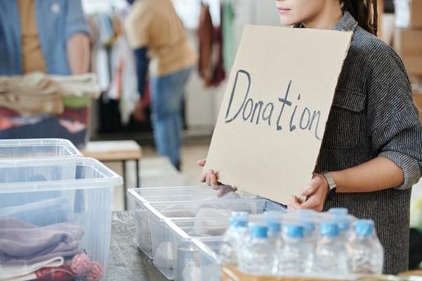 A nonprofit volunteer standing with a sign labeled “donation”