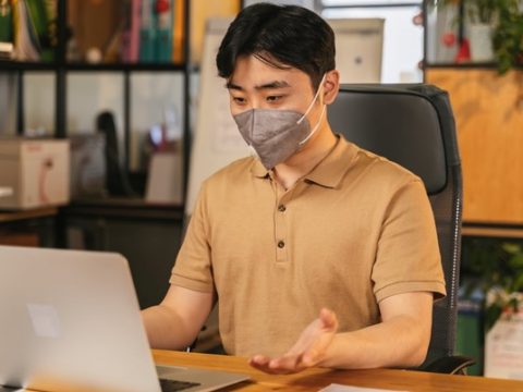 Man wearing a mask using a laptop