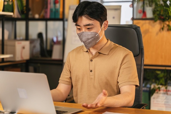 Man wearing a mask using a laptop