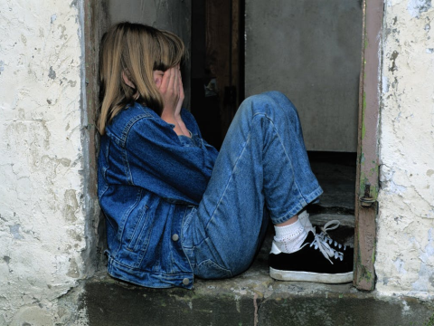 A girl wearing denim crying while covering her face