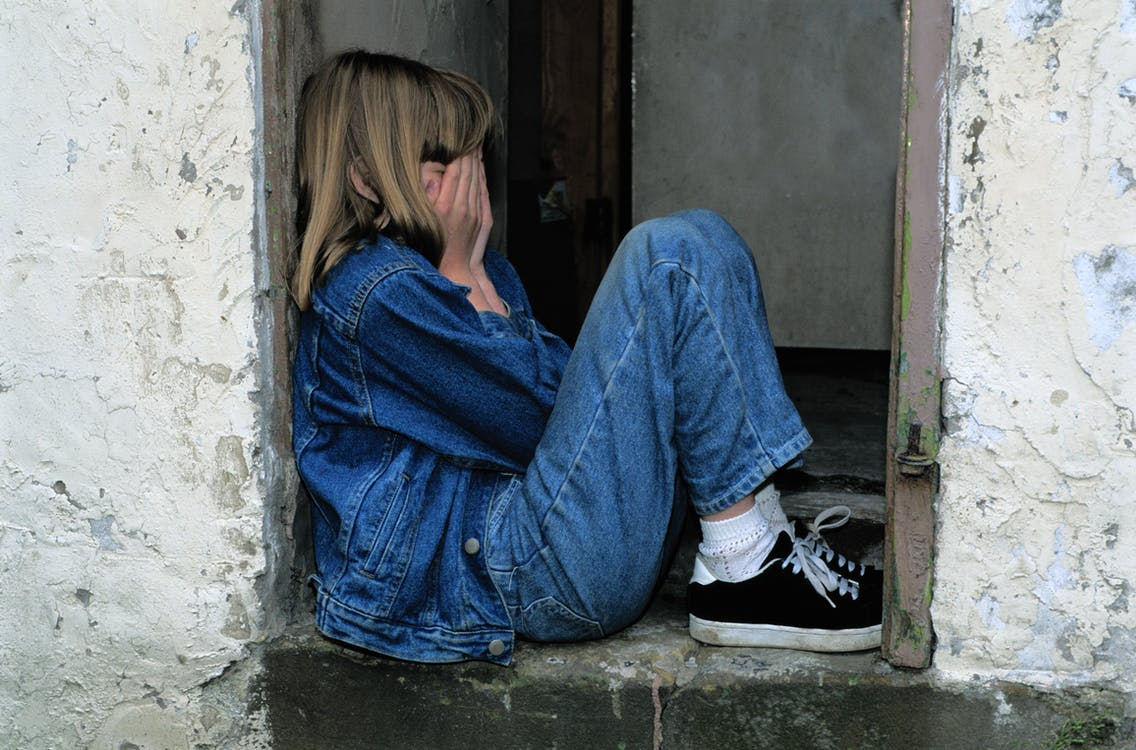 A girl wearing denim crying while covering her face