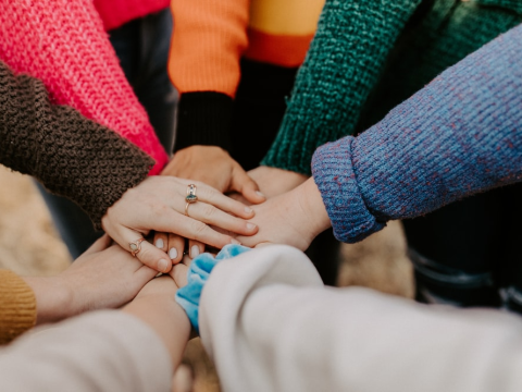 A group of people piling their hands on top of each other