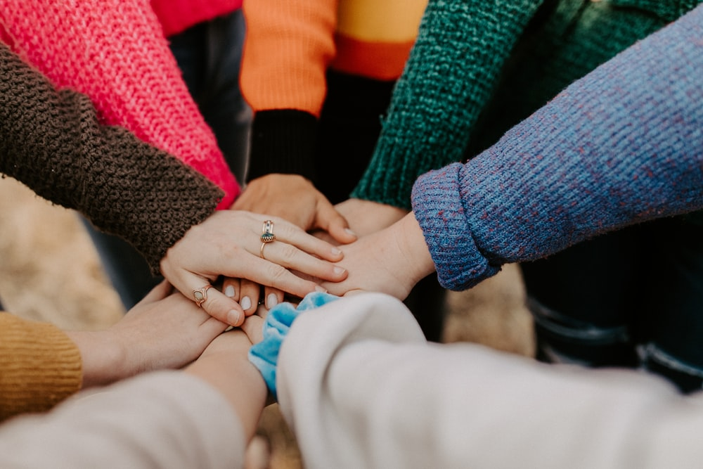 A group of people piling their hands on top of each other