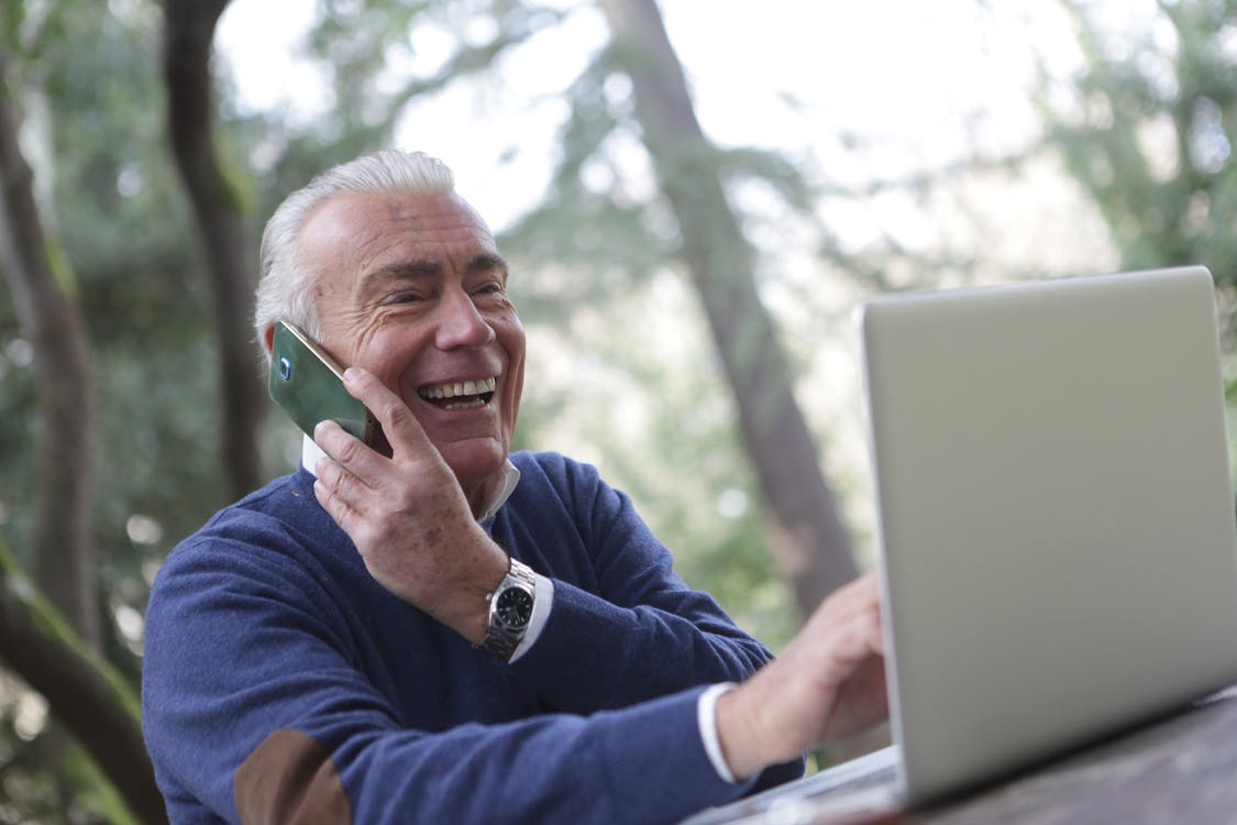  old man using cellphone and laptop